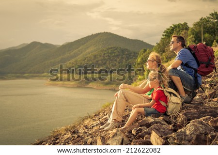 Happy family sitting near the lake at the day time. Concept of friendly family.