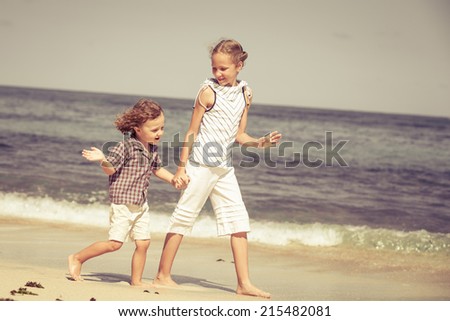brother and sister playing on the beach at the day time