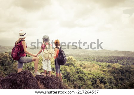 two little kids and mother standing on the mountain at the day time