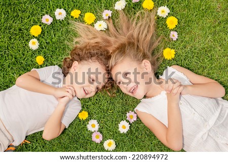 Happy little boy and girl lying on the grass at the day time. Concept of a brother and sister forever. Heart laid out on the grass of the colors, the concept of Valentine\'s Day