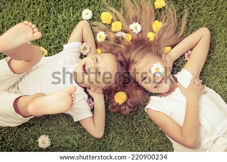 Happy little boy and girl lying on the grass at the day time. Concept of a brother and sister forever.