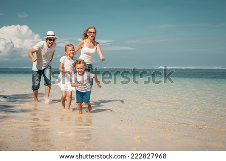 Happy family running on the beach at the day time