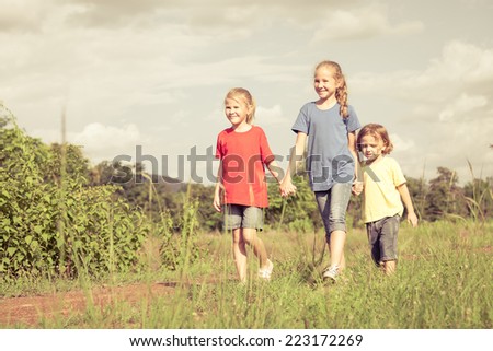 Happy brother and sisters running on the road at the day time. Concept of friendly family.