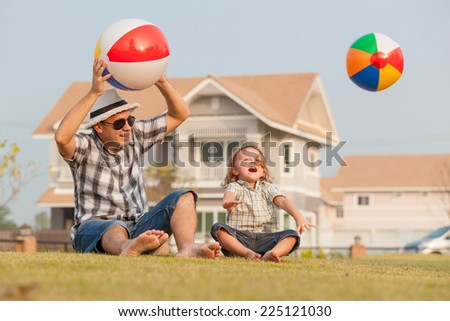 Dad and son playing on the lawn in front of house at the day time