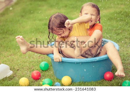 brother and sister playing with water near a house at the day time