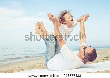 Father and son playing on the beach at the day time. Concept of friendly family.