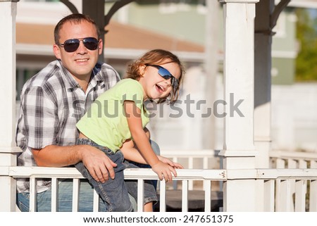 Father and son playing near the house at the day time. They sit in the white gazebo. Concept of friendly family.