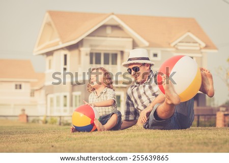 Dad and son playing with balls on the lawn in front of house at the day time
