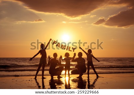 Happy family standing on the beach at the sunset time. They keep the letters forming the word \