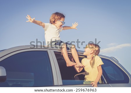 Happy brother and sister are sitting in the car at the day time
