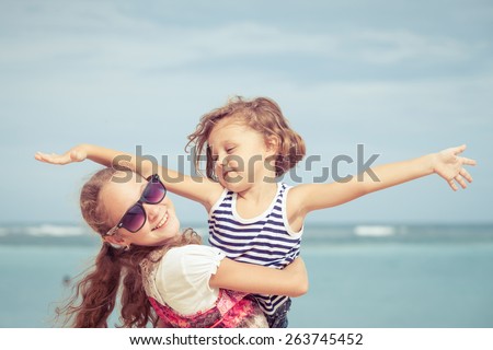 Sister and brother playing on the beach at the day time. Concept Brother And Sister Together Forever