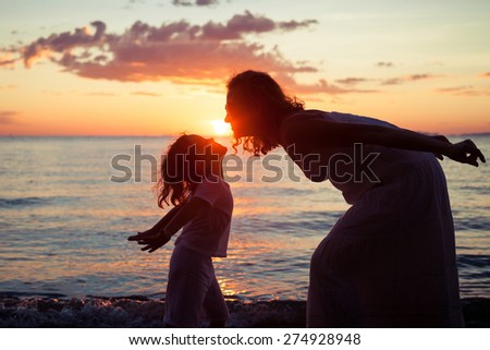 Mother and son playing on the beach at the sunset time. Concept of friendly family.