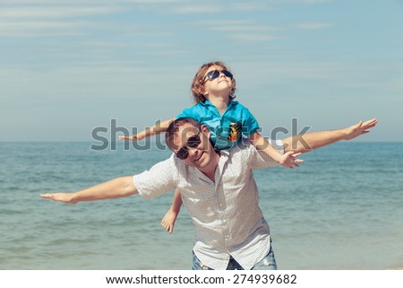Father and son playing on the beach at the day time. Concept of friendly family.
