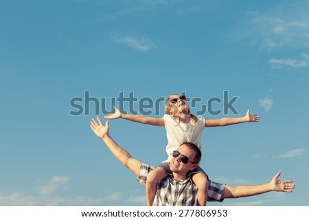 Dad and daughter in sunglasses playing near a house at the day time. Concept of friendly family.