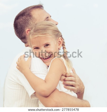 Dad and daughter  playing near a house at the day time. Concept of friendly family.