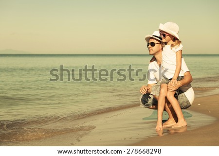 Father and daughter playing on the beach at the day time. Concept of friendly family.