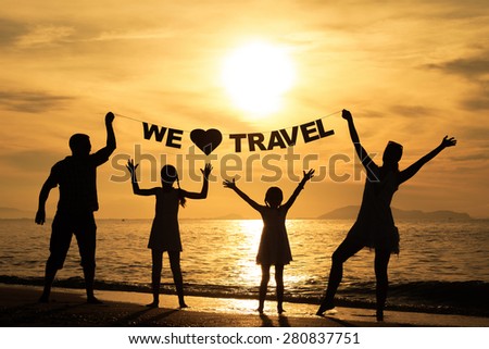 Happy family standing on the beach at the sunset time. Parents hold in the hands  inscription 