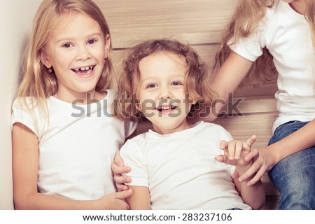 Portrait of happy children which are sitting on the stairs in the house. The concept of a brother and sister forever.