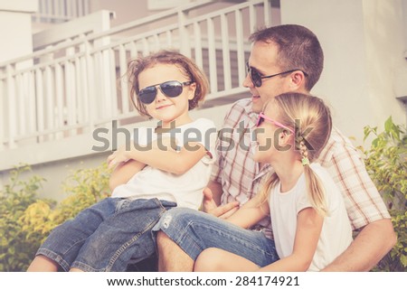 Dad and children playing near a house at the day time. Concept of friendly family.