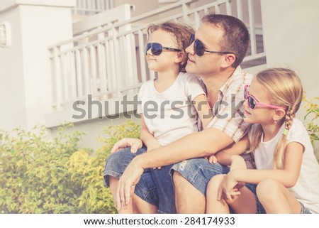 Dad and children playing near a house at the day time. Concept of friendly family.