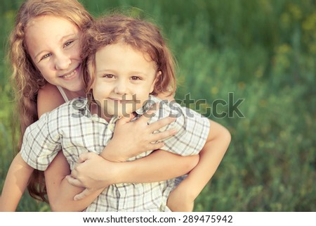 Portrait of happy children which standing in the park at the day time. The concept of a brother and sister forever.