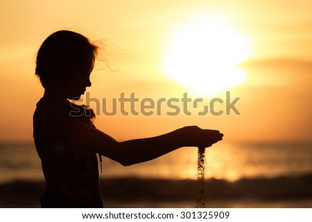 Portrait of sad teenager girl standing on the beach at sunset time.