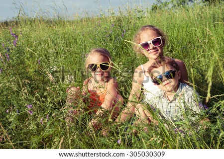Three happy children  playing near the tree at the day time. Concept Brother And Sister Together Forever