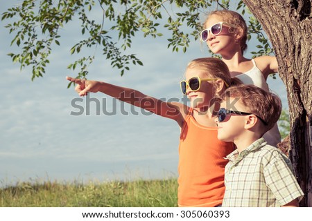Three happy children  playing near the tree at the day time. Concept Brother And Sister Together Forever