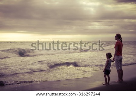 Mother and son playing on the beach at the day time. Concept of friendly family.