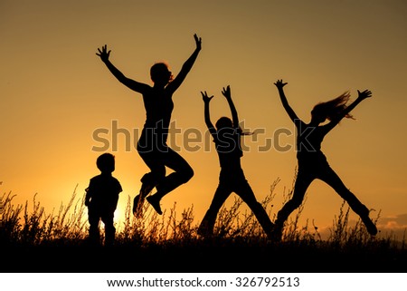Happy family jumping in the park at the sunset time.  Concept of friendly family.
