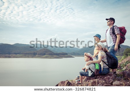 Happy family standing near the lake at the day time.  Concept of friendly family.