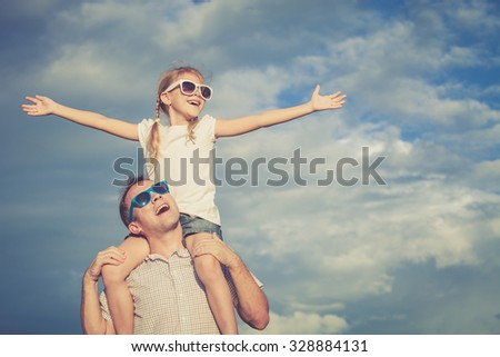 Father and daughter playing in the park  at the day time. Concept of friendly family. Picture made on the background of blue sky.