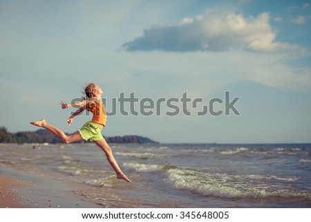Teen  girl  jumping on the beach at the day time. Concept of happy youth.