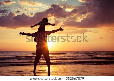 Father and son playing on the beach at the sunset time. Concept of happy friendly family.