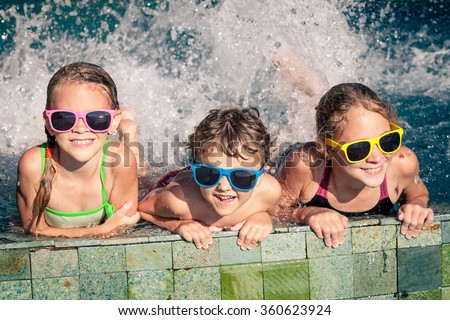 Three happy children  playing on the swimming pool at the day time. Concept of friendly family.