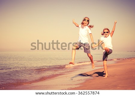 Two sisters playing on the beach at the day time. Concept of friendly sister.