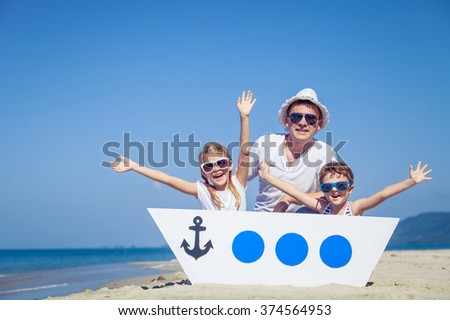Father and children playing on the beach at the day time. Concept of friendly family.