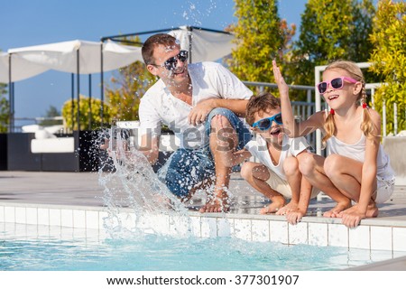 Father and children playing near a swimming pool  at the day time. Concept of friendly family.