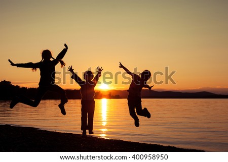 Happy children playing on the beach of lake at the sunset time. Concept of happy friendly sister and brother.