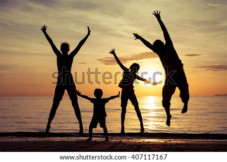 Silhouette of happy family who playing on the beach at the sunset time. Concept of friendly family.