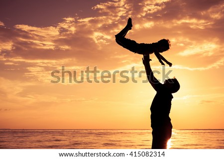 Father and son playing on the beach at the sunset time. Concept of friendly family.