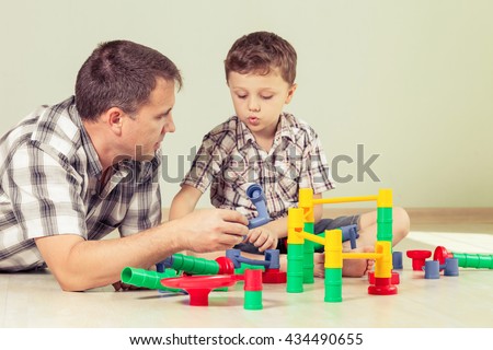 Daddy with little boy playing with toy  on the floor at the day time. Concept of friendly family.