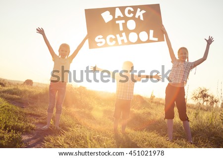 Silhouette of happy children which playing on the field at the sunset time. They having fun on the nature. Concept of the kids are ready to go to school.