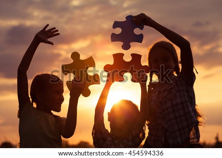 Silhouette of three happy children which playing on the field at the sunset time. They having fun on the nature. Concept of the kids are ready to go to school.