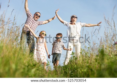 Happy family walking on the field at the day time. People having fun on the park. Concept of friendship forever and of summer vacation.