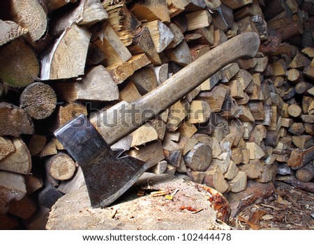 Old axe in log on a firewood background