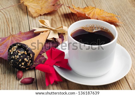 Cup of coffee with cakes in cream cone and bow out of paper