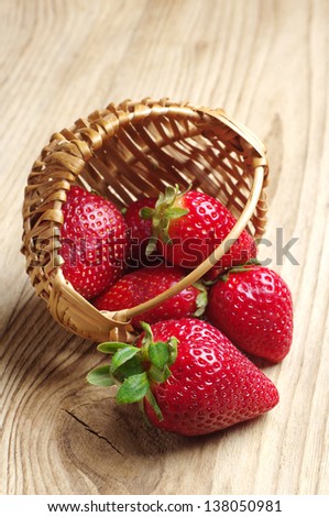 Strawberries in a basket and near on a wooden table