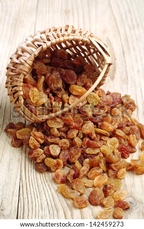 Raisin in a wicker basket and near on wooden table
