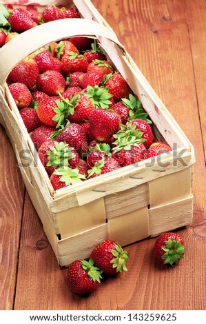 Strawberries in a wooden basket and near on table